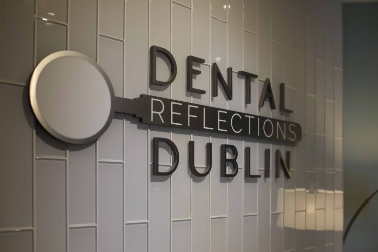 gray wall of tiles with Dental Reflections Dublin logo on it