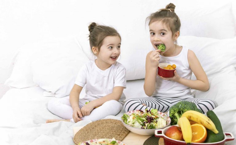 kids eating healthy food while sitting on a bed
