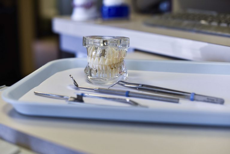 dental hygienist tools sit next to a mouth mold
