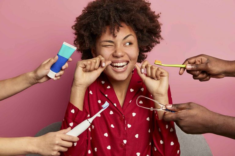 woman flossing teeth while a toothpaste, toothbrush, tongue scraper, and toothbrush are offered to her