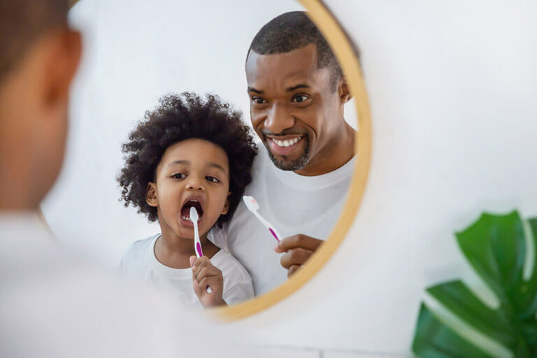 child brushing teeth with their parent
